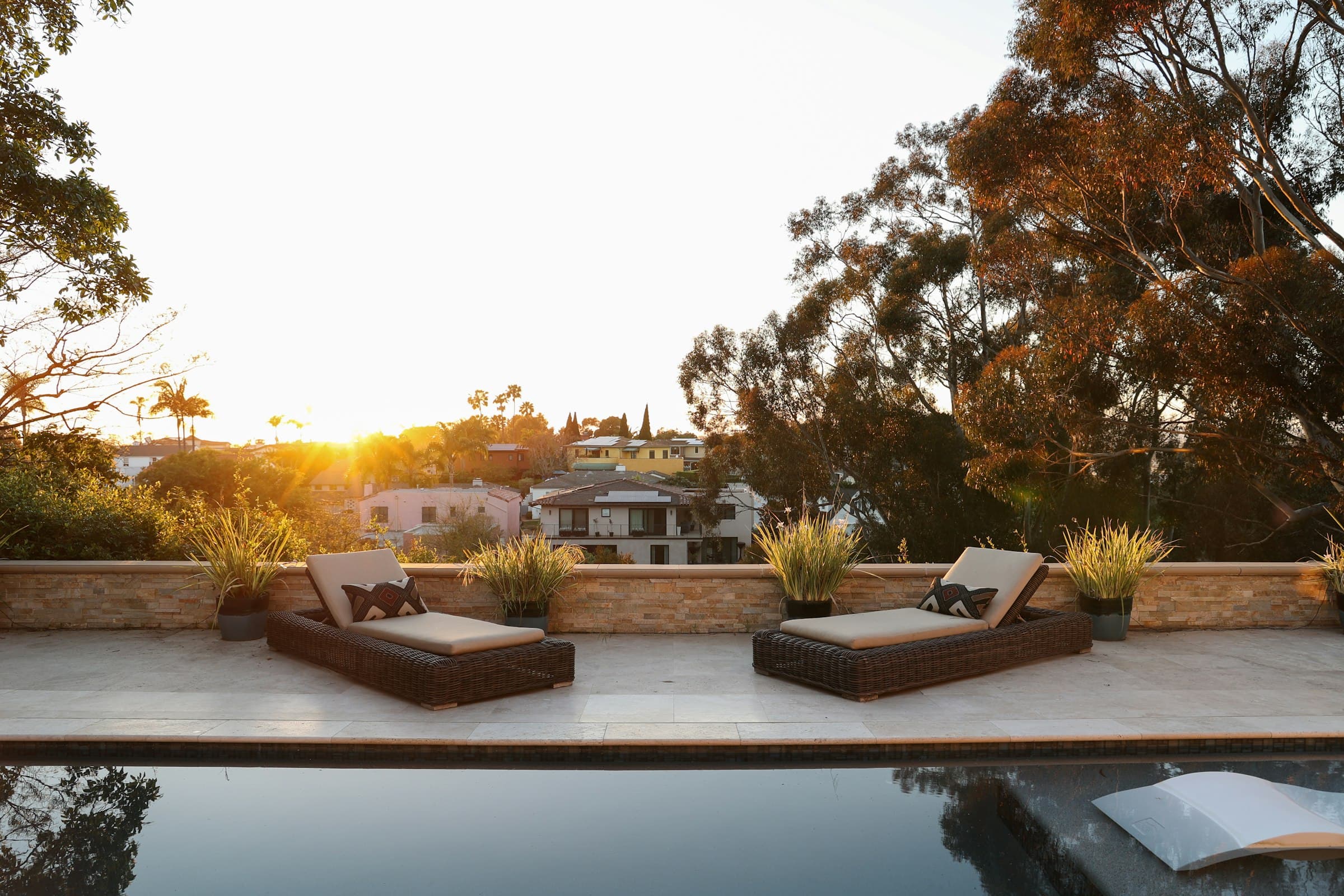 Loungers beside a backyard pool at sunset.